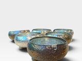 four blue and green bowls sitting on top of a white surface