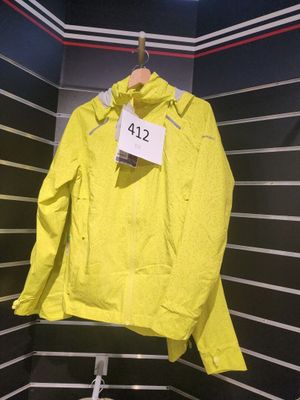 une veste jaune suspendue à un cintre dans une pièce aux murs rayés de noir et blanc