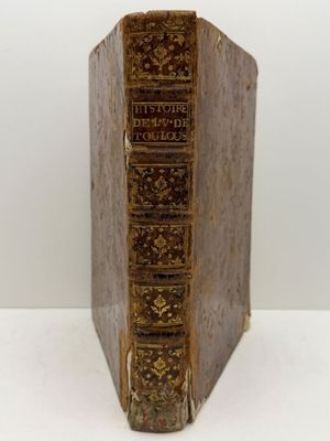 un vieux livre posé sur une table blanche à côté d'un mur blanc