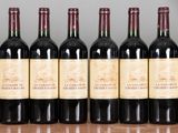 six bottles of red wine are lined up on a table