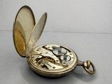 a gold pocket watch sitting on a table with a chain