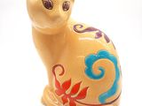 une figurine de chat jaune posée sur une surface blanche