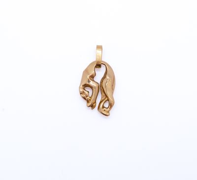 a close up of a gold pendant on a white surface