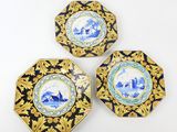 three blue and white plates with gold designs on them on a white surface