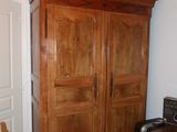a wooden armoire in the corner of a room