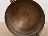 an old metal bowl sitting on top of a wooden table