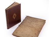 an old book sitting next to an old book on top of a white surface