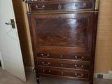 une commode dans un coin d'une chambre où se trouve un lit