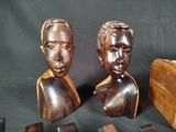 two wooden busturines of a man and a woman on a black background