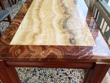 a wooden table with a marble top in the middle of a room