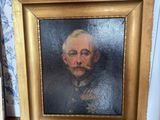 tableau représentant un homme moustachu, dans un cadre doré, posé sur un plancher en bois