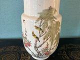 un vase blanc orné d'oiseaux, posé sur une table