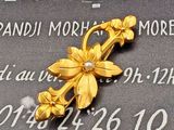 une broche en forme de fleur en or posée sur une plaque