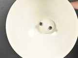 an overhead view of a person holding a white bowl with a hole in it