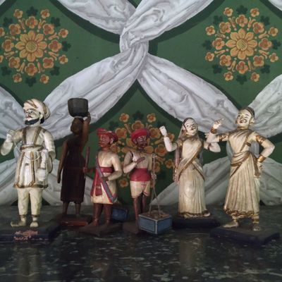 cinq figurines représentant des personnes debout devant un mur vert et blanc