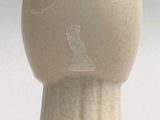 a white vase with a bird on it on a table