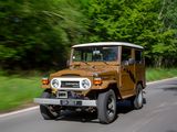 a brown jeep driving down the road with trees in the background