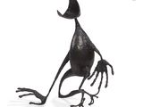 a metal sculpture of a bird that is sitting on the ground