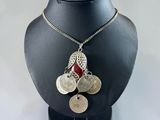 silver necklace with coins and a red ribbon on a mannequin
