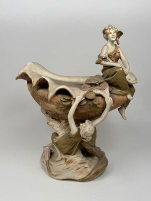 une figurine représentant une femme assise sur un vase