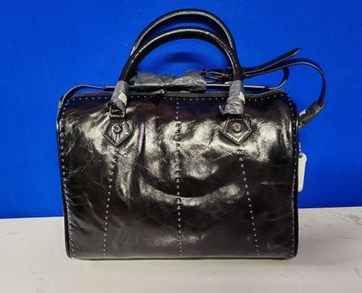 un sac à main en cuir noir posé sur une table blanche