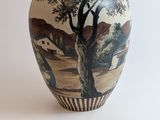 a vase with a painting on it sitting on a table