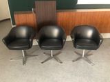 trois fauteuils en cuir noir placés les uns à côté des autres dans une pièce