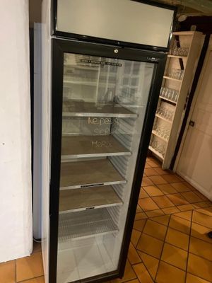 un réfrigérateur vide dans une cuisine au sol carrelé