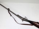 an old gun with a wooden handle and a leather sling on a white surface
