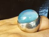 a person holding a ring with a blue stone on it