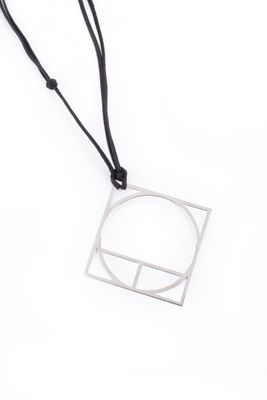 un collier composé d'un carré en argent et d'un cordon noir sur fond blanc