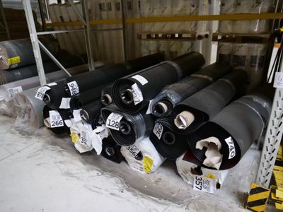 de nombreux rouleaux de plastique noir sur une étagère dans un entrepôt