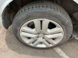 a cat sitting on the tire of a white car