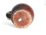 a brown and black vase sitting on a white surface