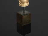 a carved ivory head of a man on a pedestal with a black background