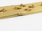 an image of a close up of a gold bracelet with pink stones