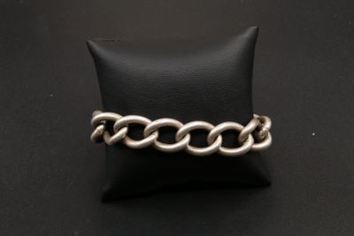 un gros plan d'un bracelet à chaîne en argent posé sur un coussin noir