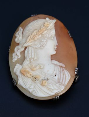 une image représentant le profil d'une femme sur une broche en forme de coquillage