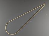un collier en or avec une chaîne posée sur une surface grise