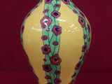 un vase jaune orné de fleurs rouges sur fond rouge