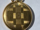 a gold pocket watch on a white surface with a chain