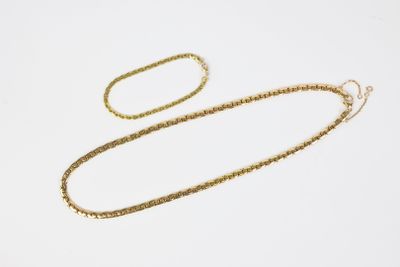 a gold necklace and bracelet set on a white background