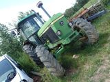 a tractor that is parked in the grass next to a car