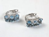 une paire de boucles d'oreilles en topaze bleue sur un fond blanc
