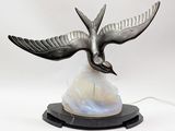 une sculpture représentant un oiseau en plein vol au-dessus d'un rocher