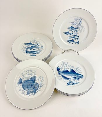 quatre assiettes bleues et blanches ornées de motifs de poissons sur fond blanc