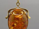 an image of a gold pendant with a large amber stone