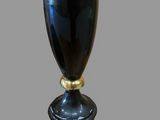 a black vase with a gold base on a table