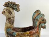 a colorful bird shaped planter sitting on a white surface