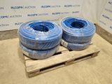 Deux tuyaux bleus sont empilés sur une palette devant un mur.